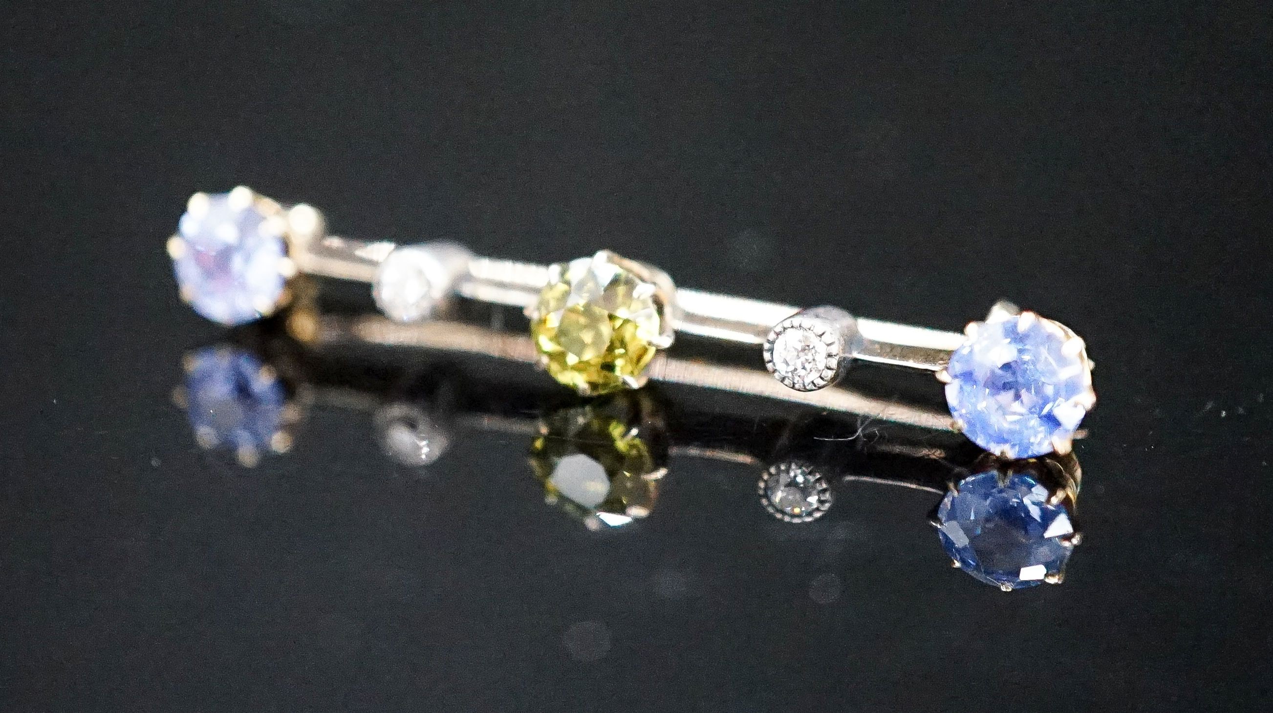 A yellow metal, single stone garnet?, two stone Ceylon sapphire and two stone diamond chip set bar brooch, 37mm, gross weight 2.8 grams.